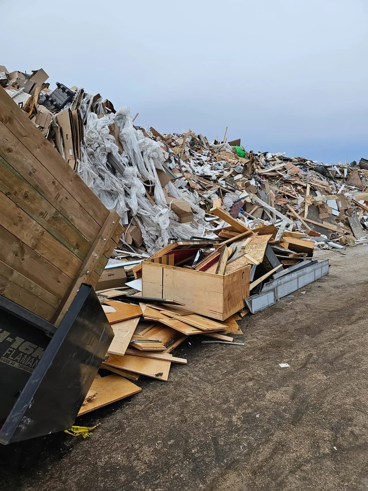 A large pile of construction and demolition debris beside a disposal bin